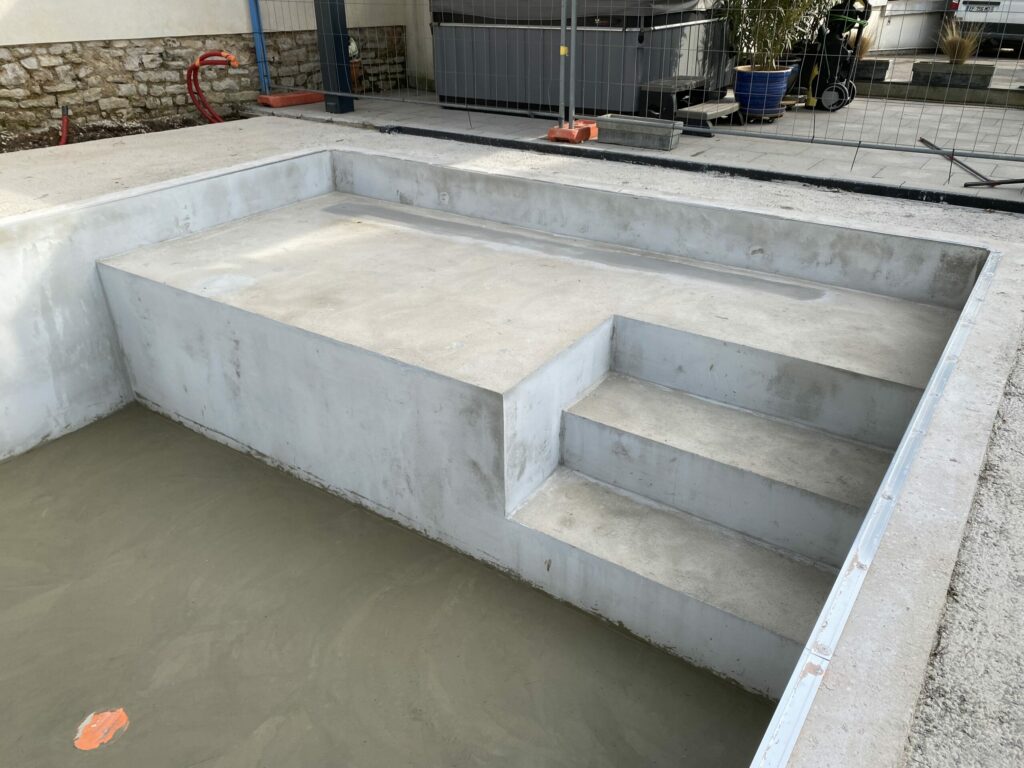 Structure béton de la piscine terminée avec plage et escaliers