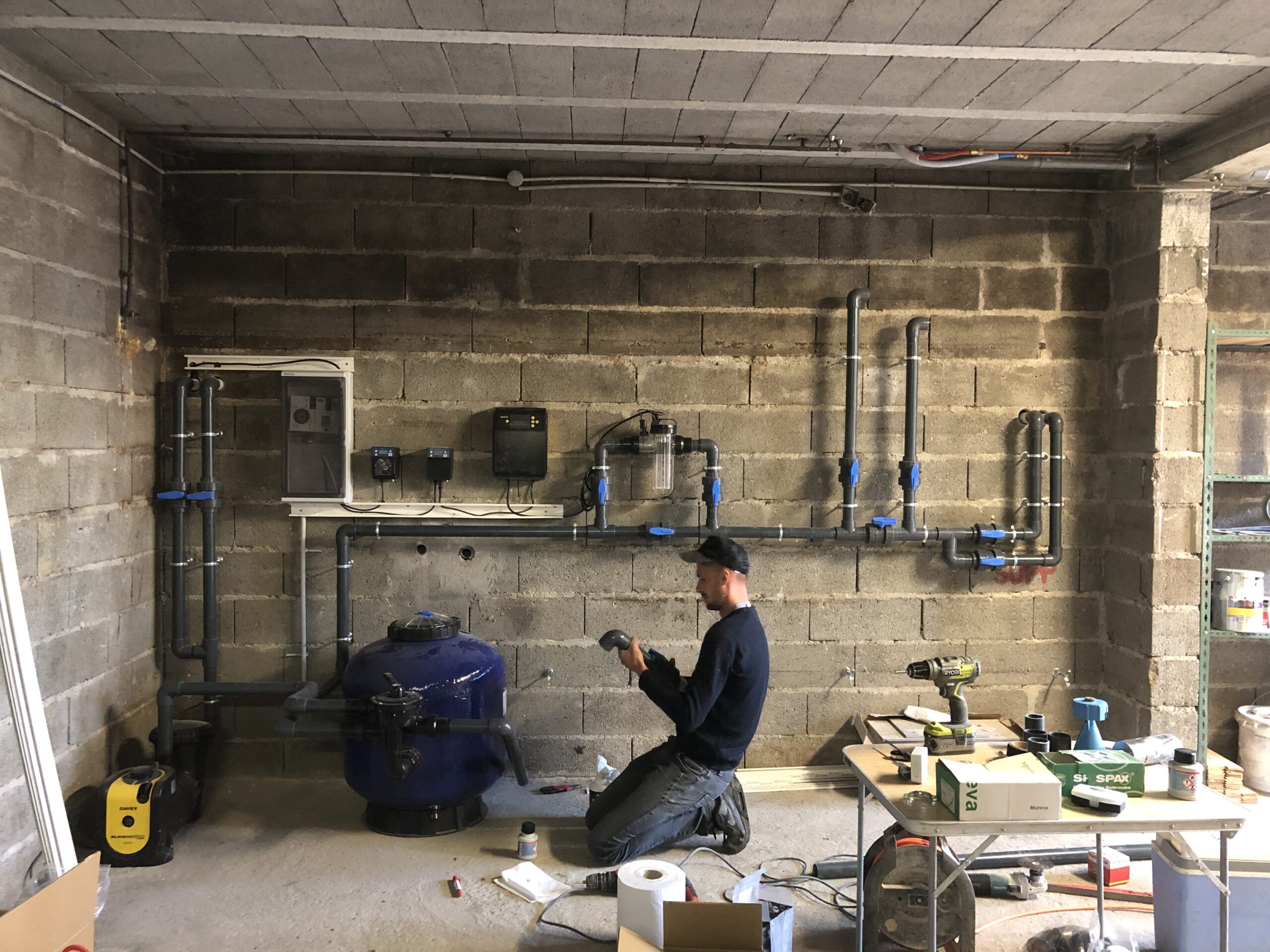 Technicien installant la pompe de filtration dans un local technique