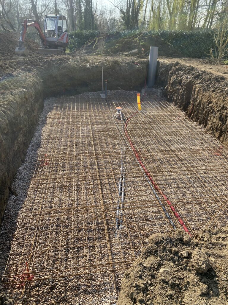 Vue d’un terrassement avec tuyauterie et ferraille posées, avant bétonnage